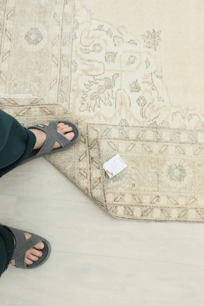 Overhead view of a foot on the rug, showing the low pile and a small white tag