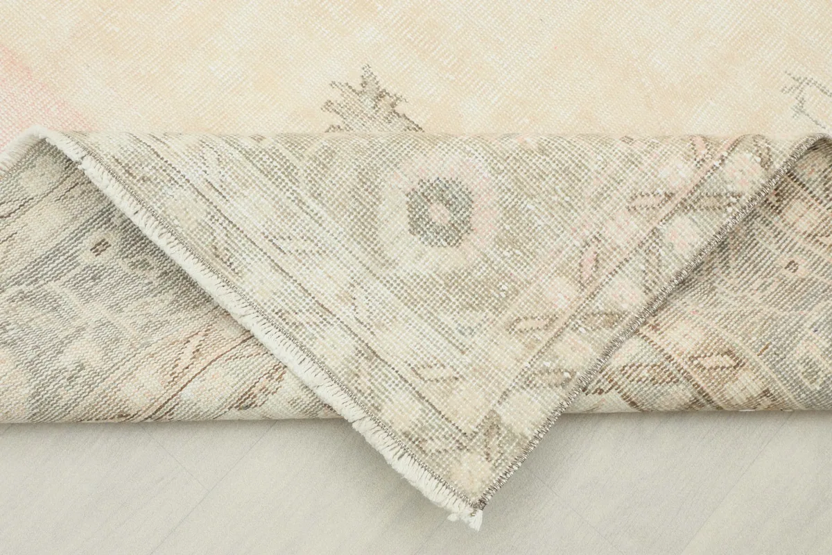 Folded corner of the rug revealing the backside and the hand-knotted cotton foundation