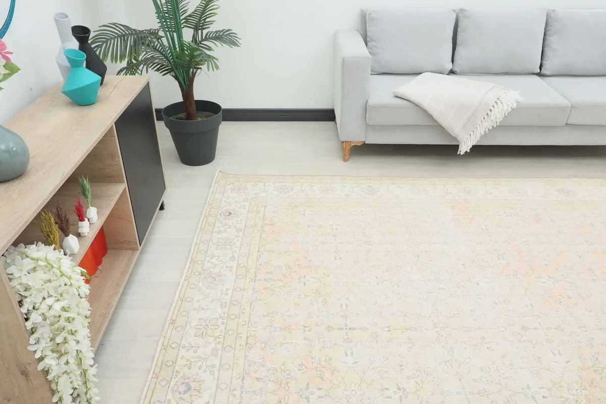 Angle view of the beige rug in a room setting, showing its scale next to a sofa and console table