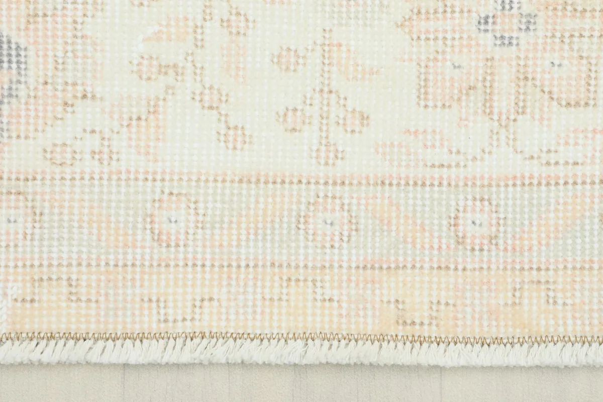 Close-up detail of the rug's border and a section of the main field, showing subtle orange and cream tones