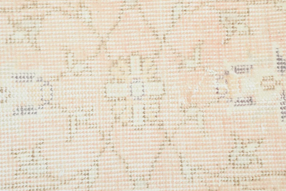 Close-up of the low wool pile texture and the faded, muted colors of the vintage rug