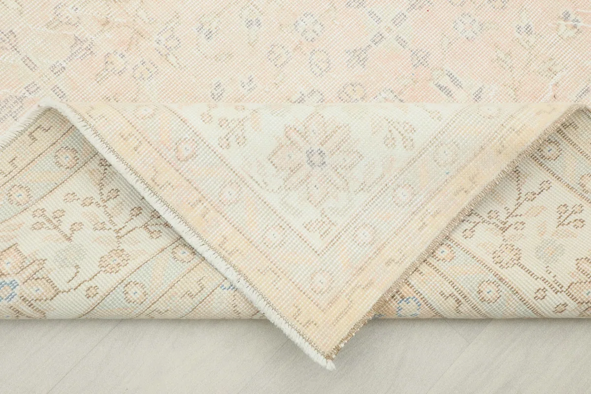 Corner of the rug folded back, revealing the cotton foundation and the reverse side of the hand-knotted construction