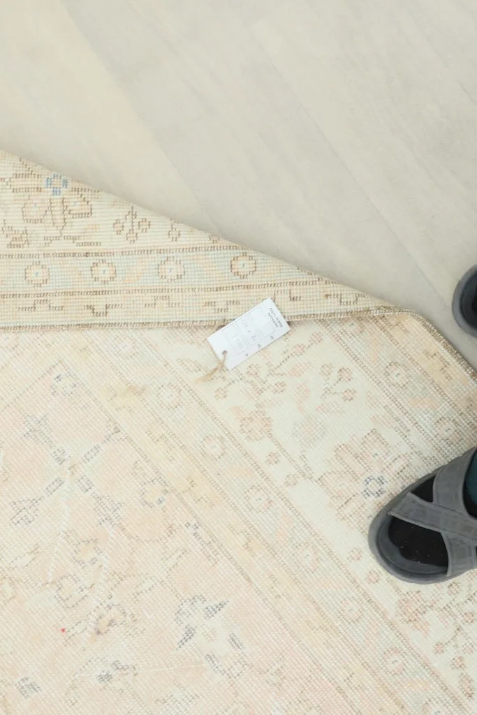 Overhead view of a section of the rug, with a tag and a pair of sandals for scale reference