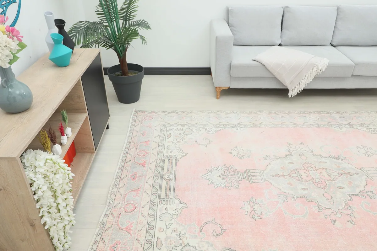 Angled view of the rose area rug in a room setting, highlighting its placement next to furniture