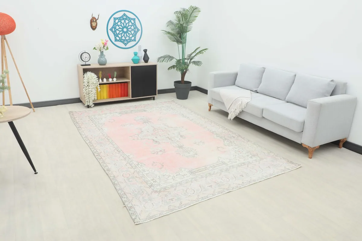 Vintage Anatolian rose area rug displayed in a bright room with a light gray sofa and modern decor