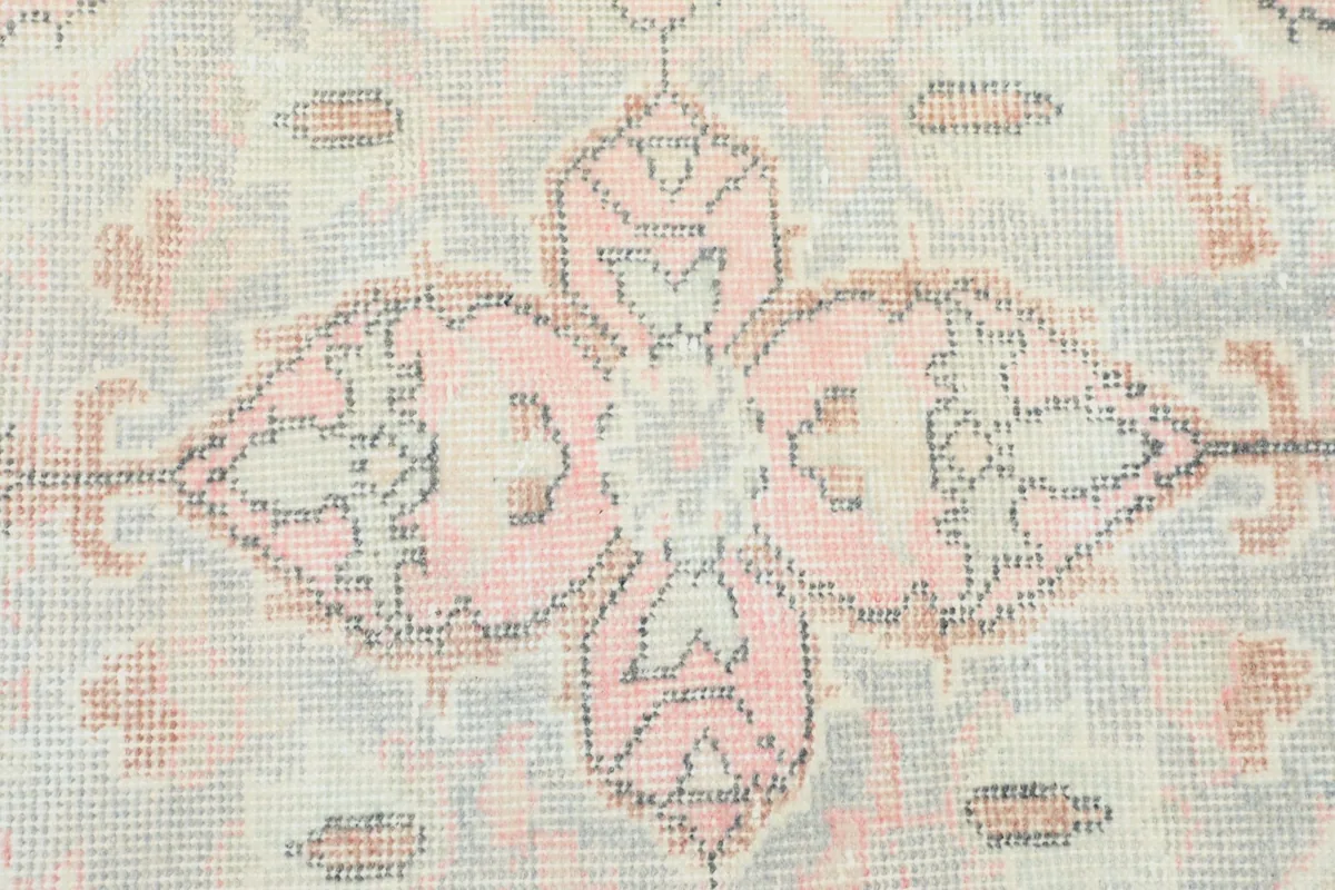 Close-up showing the intricate patterns and soft rose, cream, and gray colors in the rug's design