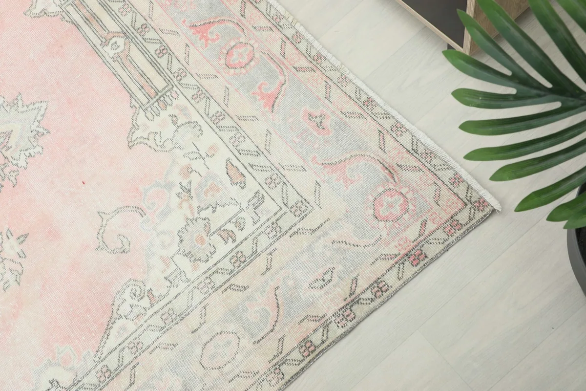 Close-up of the rug's border with geometric and floral motifs in cream and gray tones