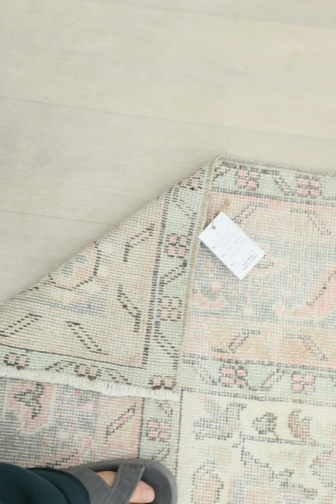 Close-up of the rug's reverse side, showcasing the hand-knotted construction and material tag
