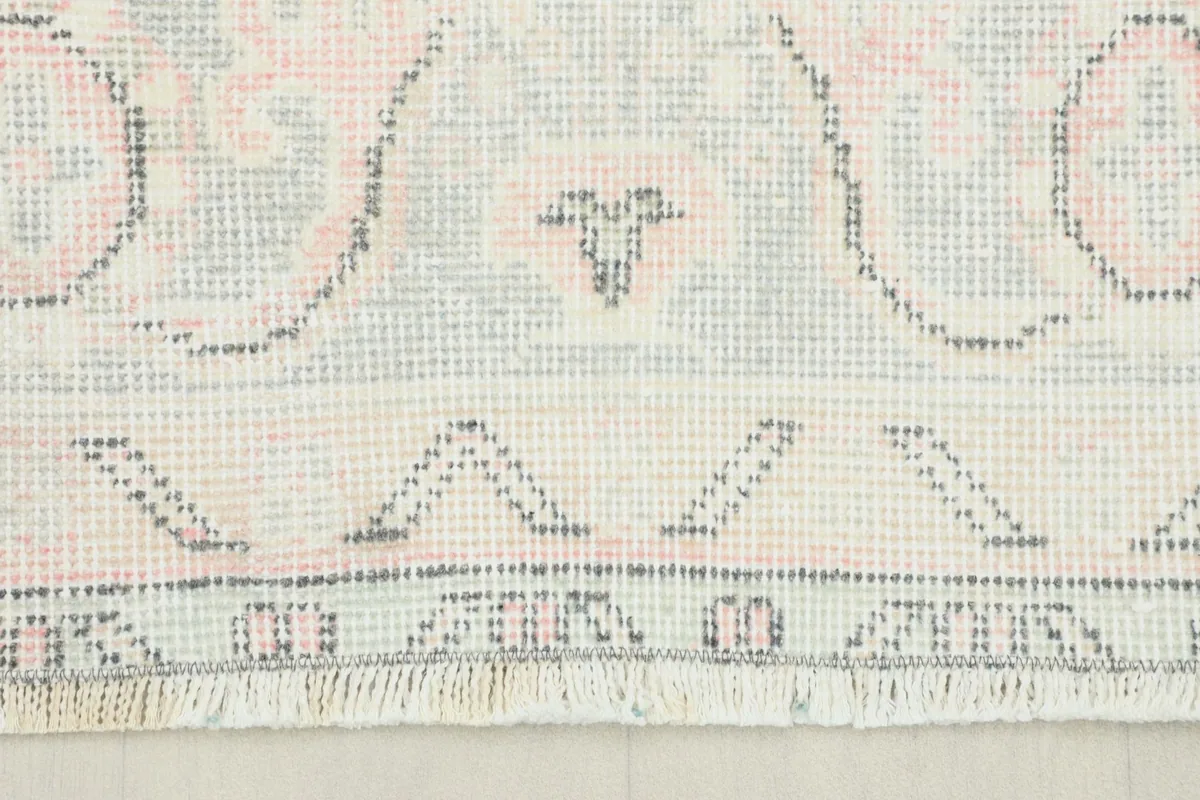 Close-up of the short, neatly finished fringe and a corner of the hand-knotted wool rug