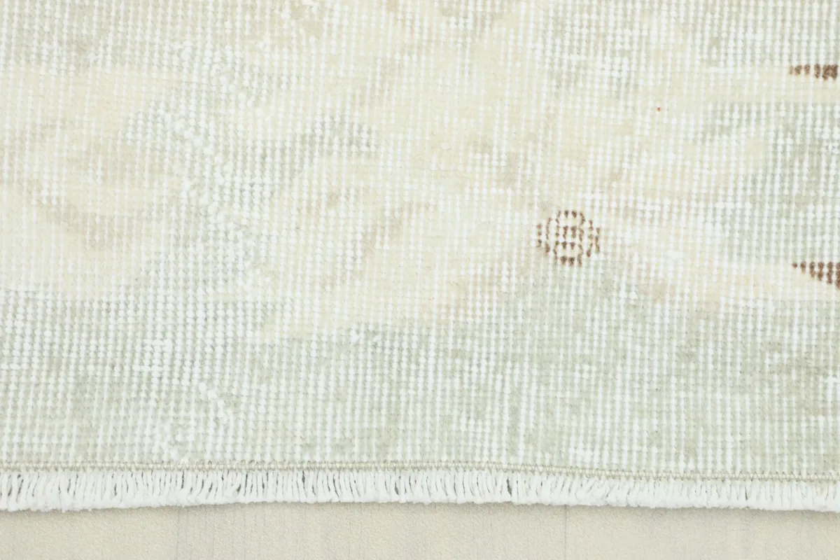 Close-up view of the faded beige pile and subtle geometric patterns on the vintage Anatolian rug.