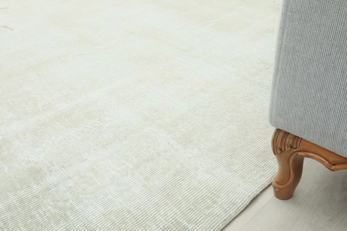 Close-up of the rug's edge and texture, positioned next to a sofa leg.