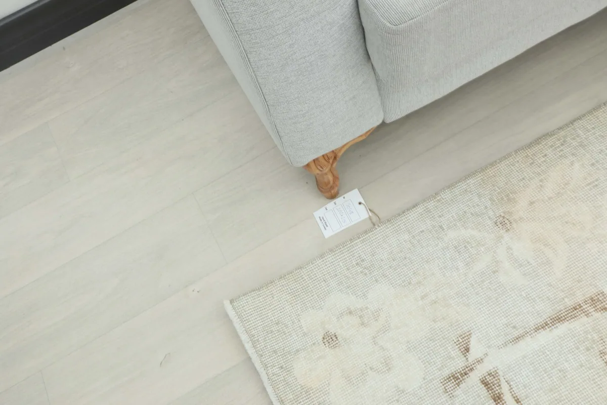 Overhead view showing the rug's texture and a small tag near the leg of a sofa.