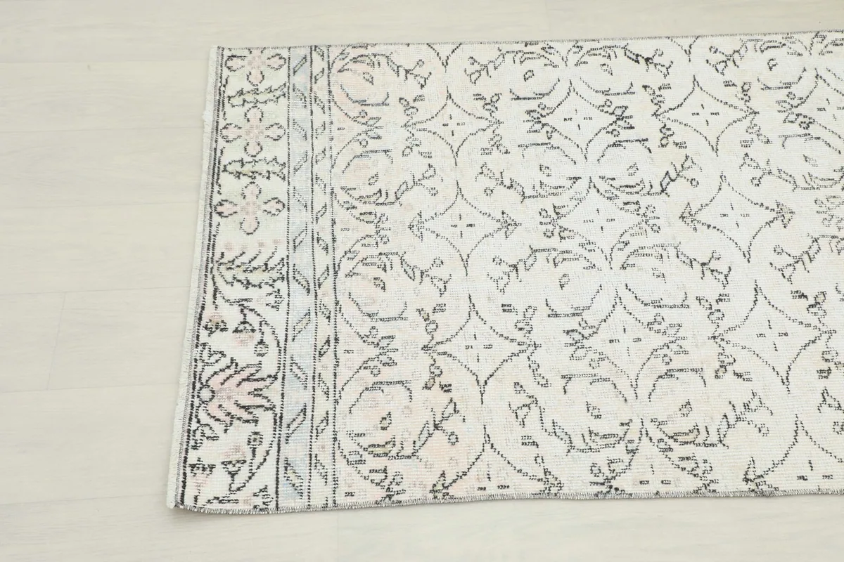 Close-up of the upper half of the rug, detailing the charcoal geometric and floral motifs.
