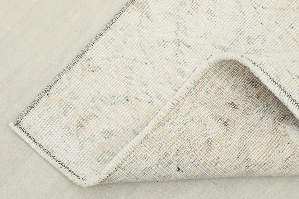 Corner of the rug folded to reveal the cotton foundation and the reverse side of the hand-knotting.