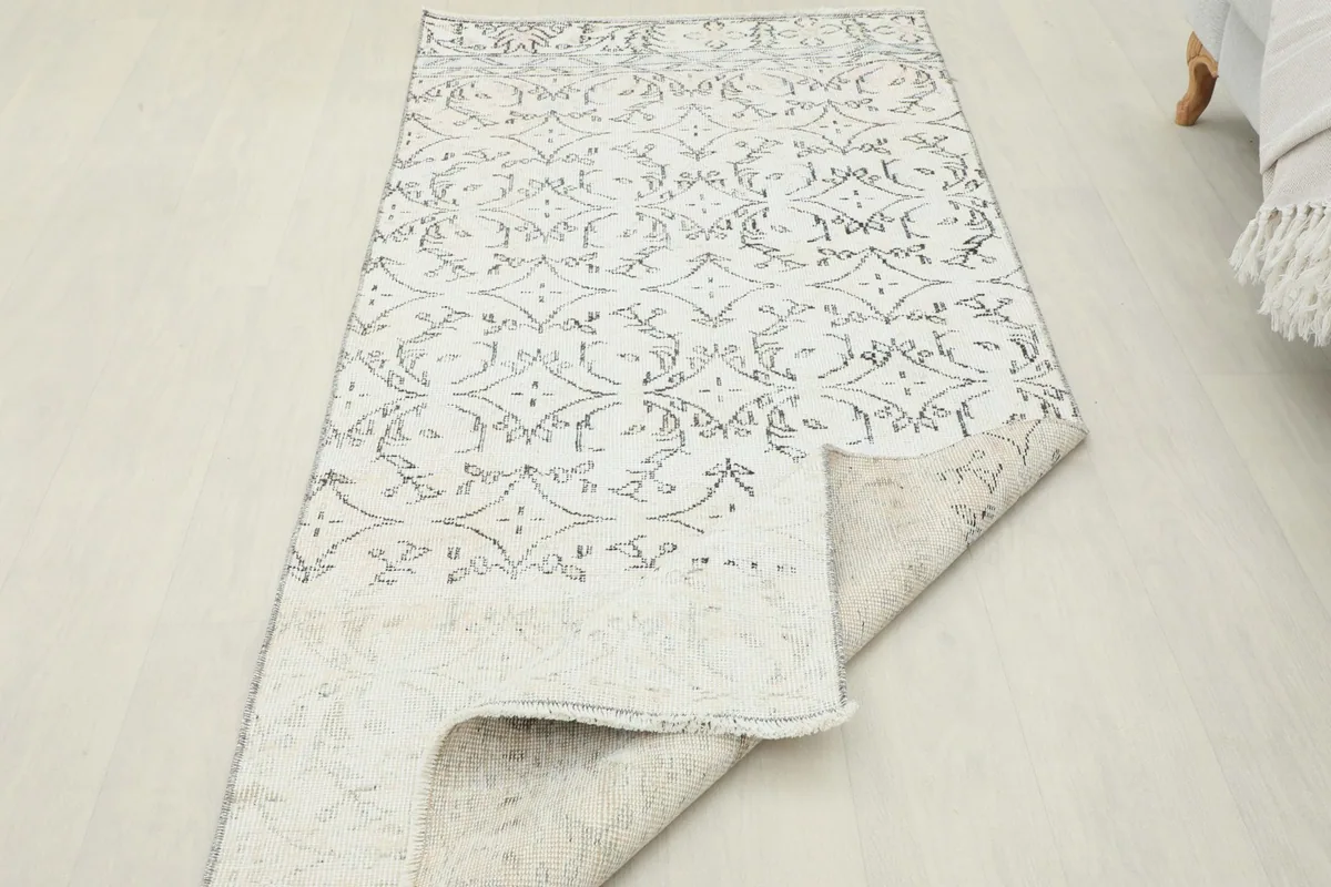 Rug partially folded, showcasing the thickness and flexibility of the vintage wool construction.