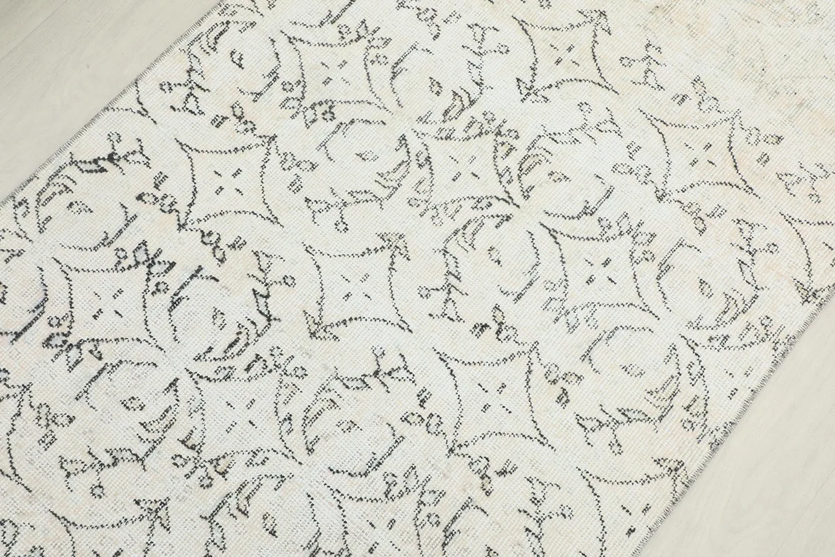 Overhead view focusing on the central pattern of the ivory and charcoal hand-knotted runner.