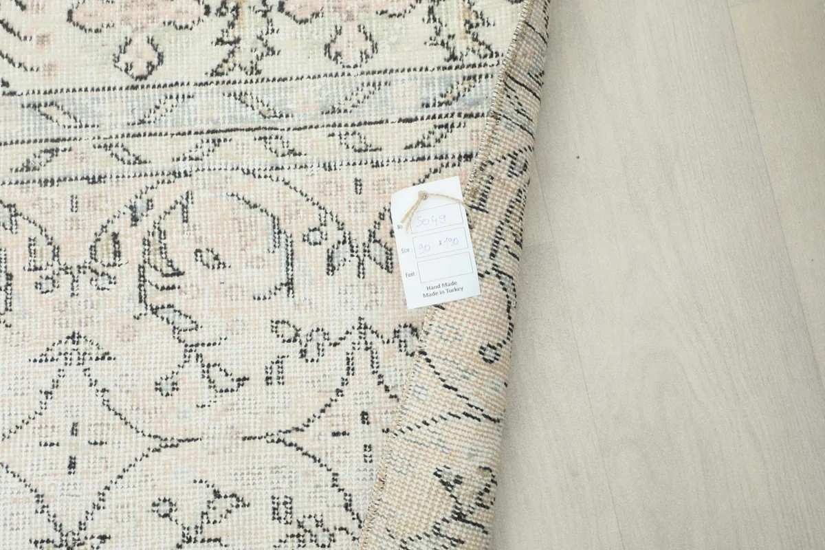 Corner of the rug with a tag, showing the reverse side and the hand-knotted detail.