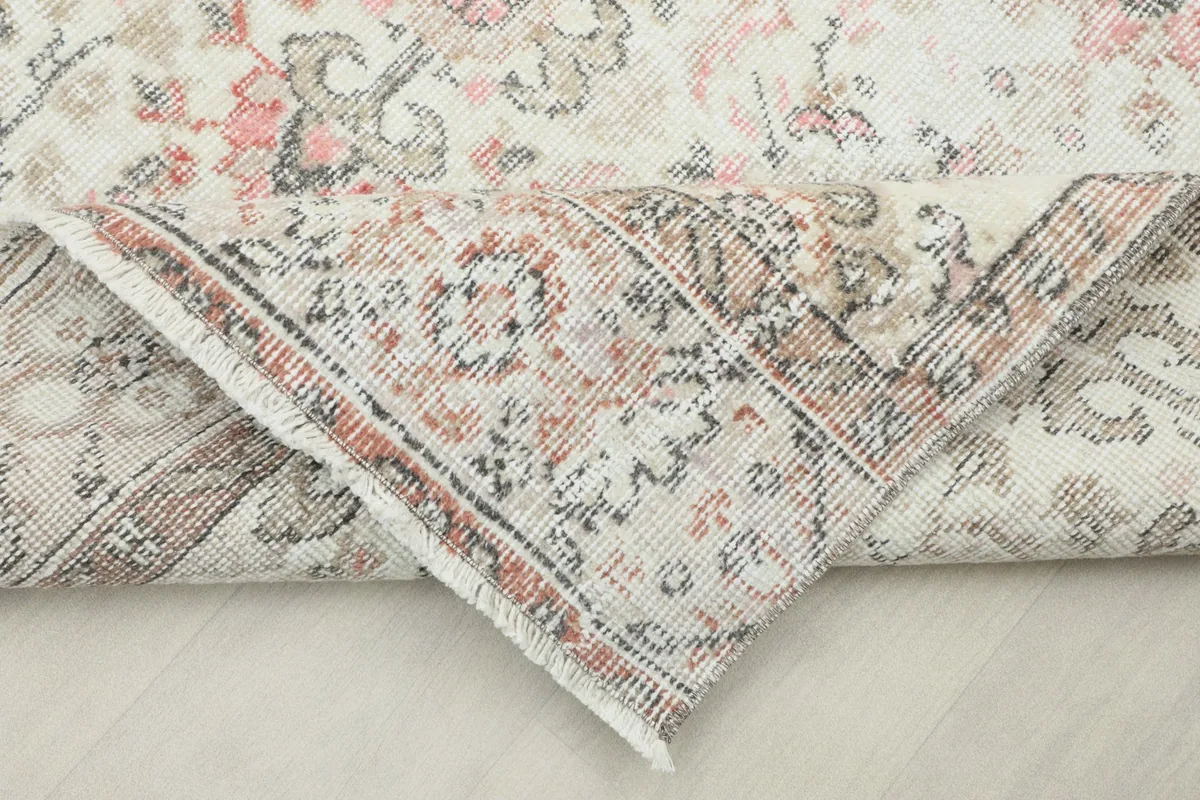 Corner of the rug folded back, revealing the reverse side of the hand-knotted wool and cotton foundation.