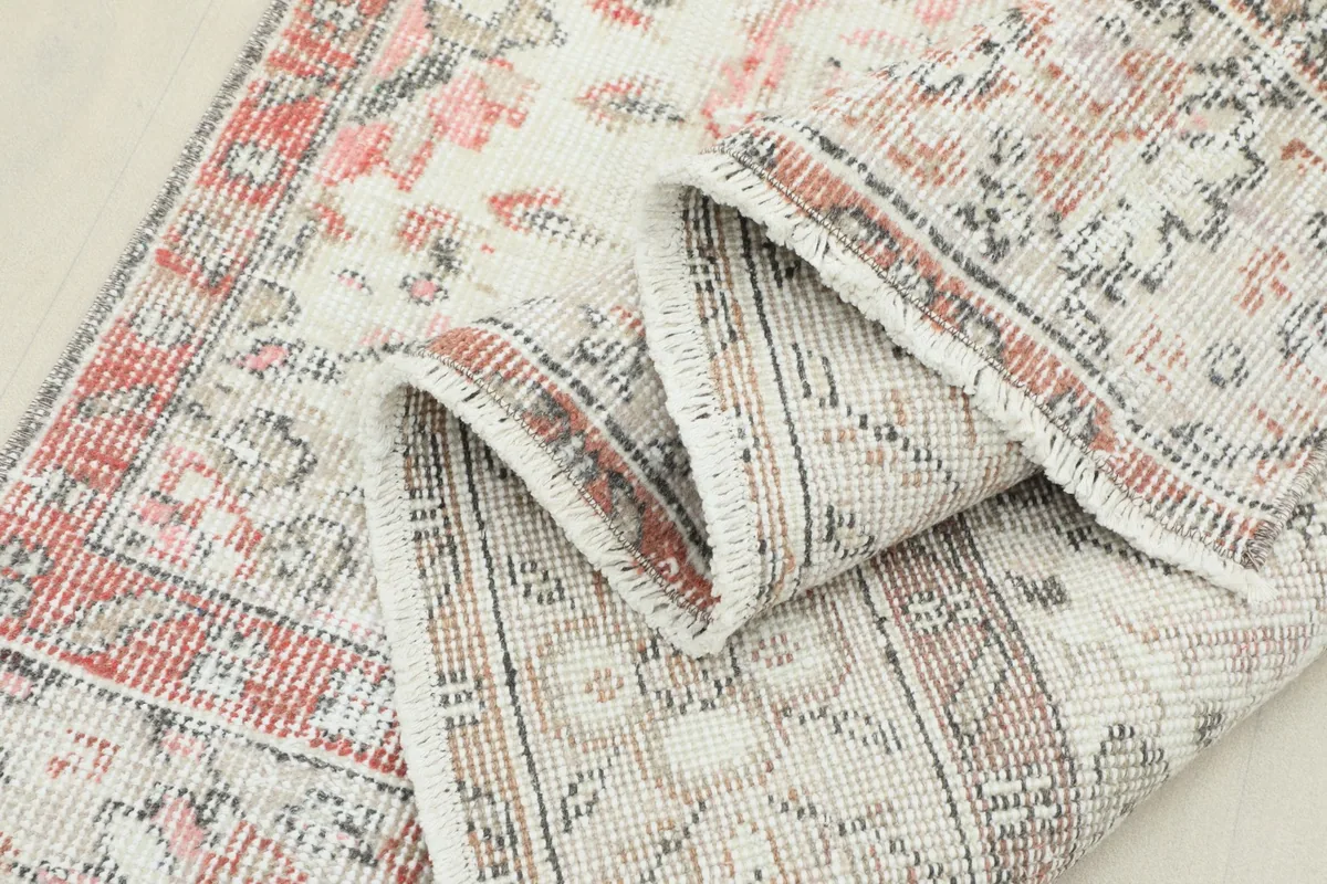 Rug folded to show the flexibility and construction, with a view of the intricate border design.