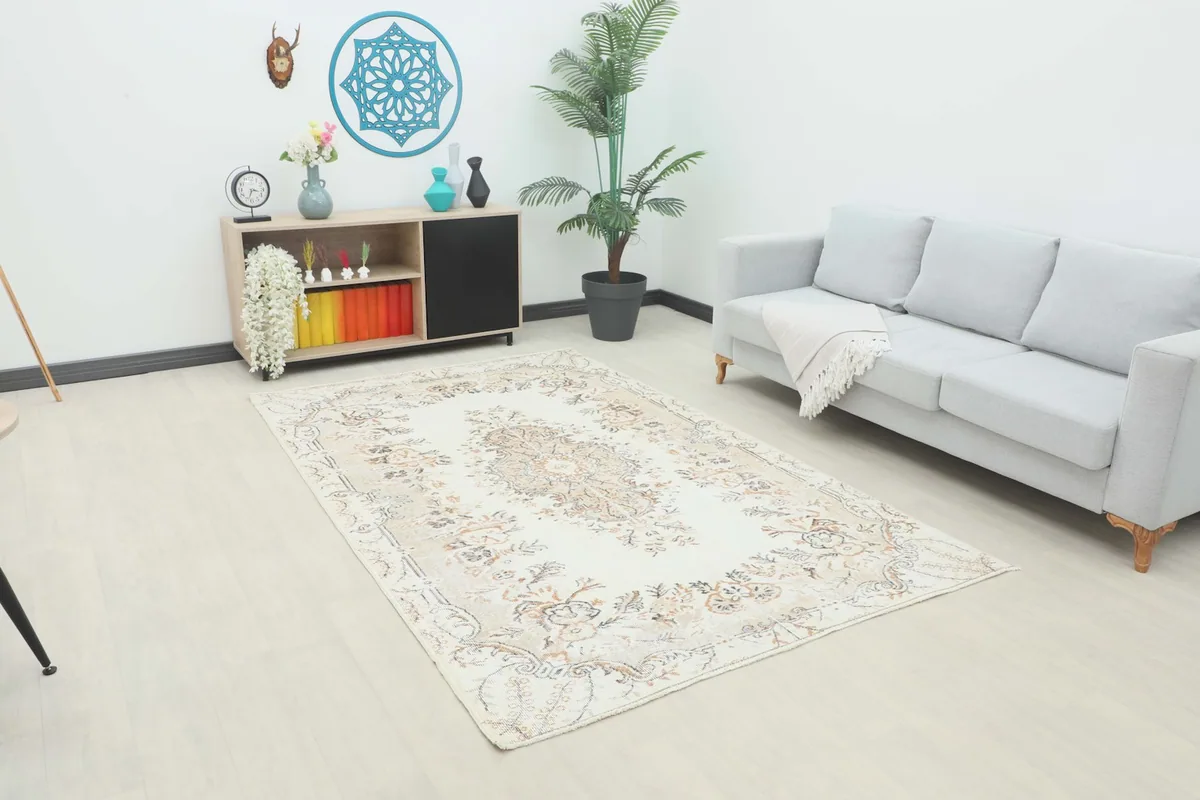 Cream and beige floral rug displayed in a bright living room setup with a sofa