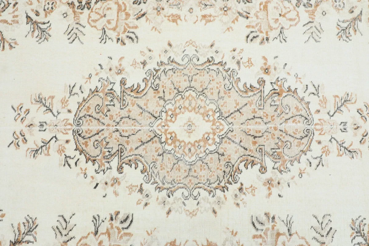 Detailed view of the central medallion design on the cream vintage rug