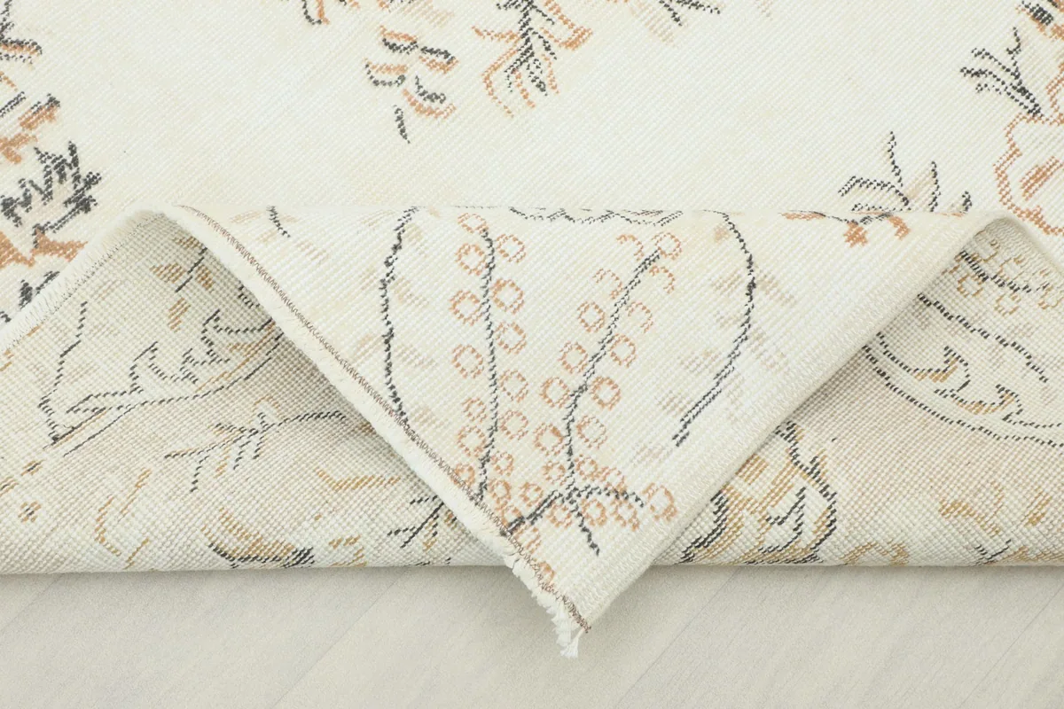 Folded corner of the rug, revealing the wool pile and cotton foundation texture