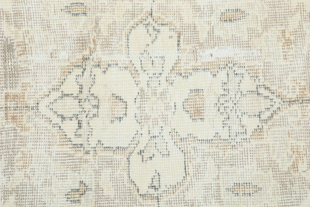 Close-up of a floral motif within the medallion, showing gentle wear and varying shades of gray.