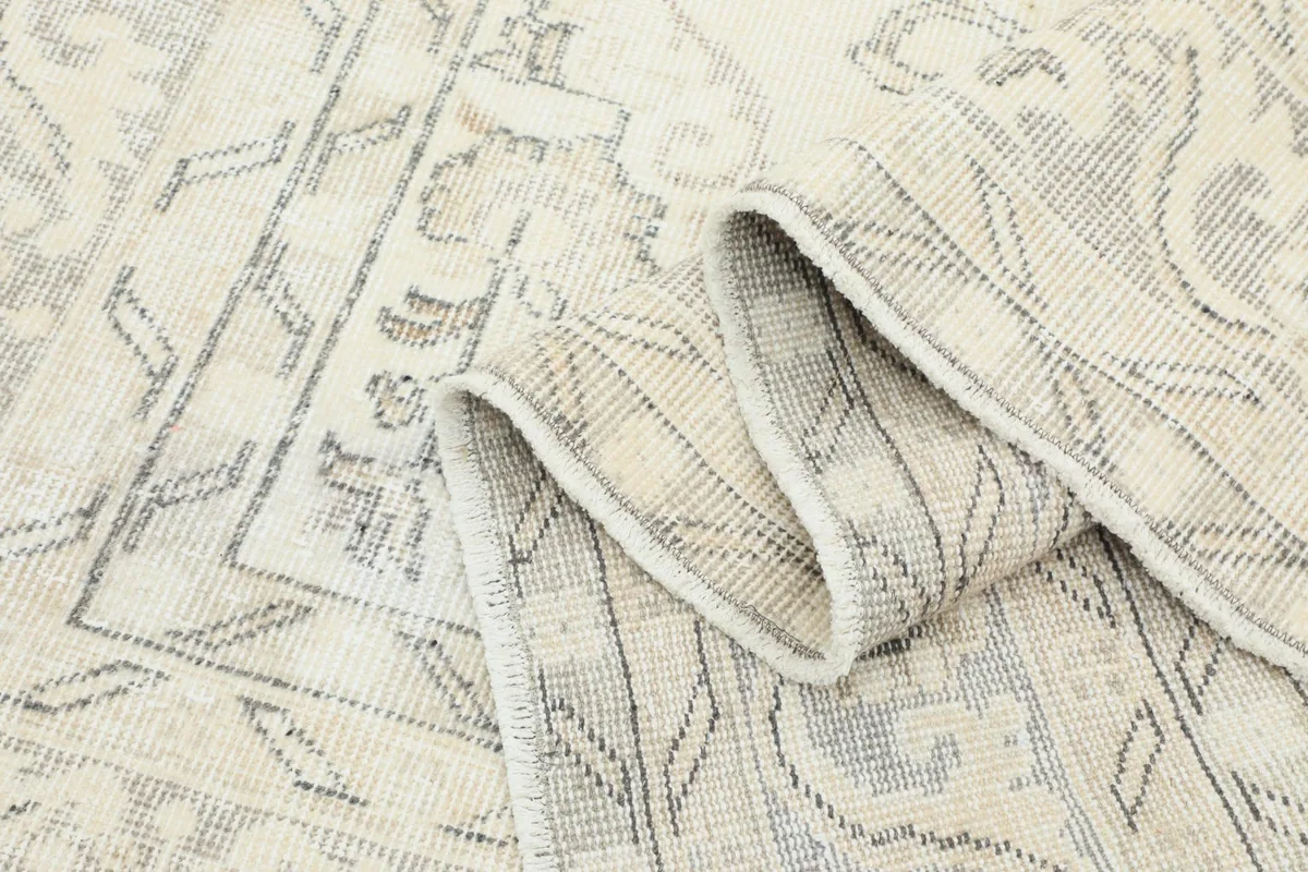 Texture close-up of the low wool pile and intricate hand-knotted details of the rug.