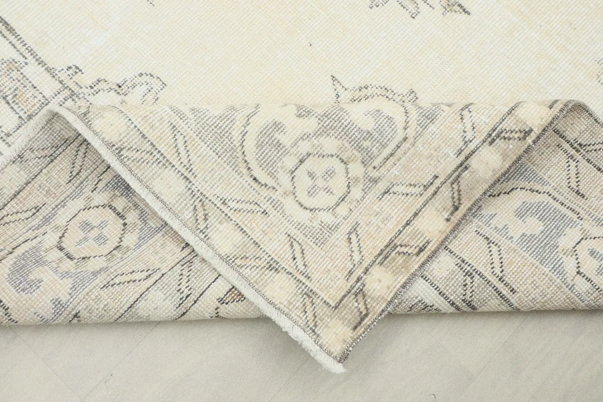 View of the folded rug corner, showing the back of the hand-knotted construction and fringe.