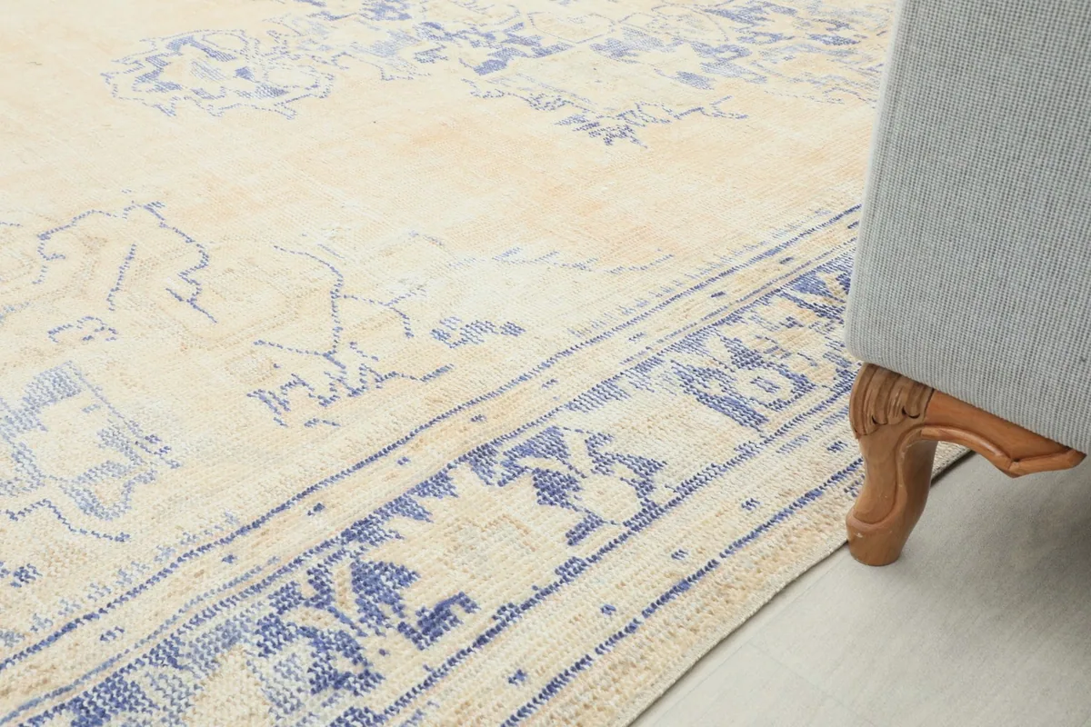Ground-level view of the rug's border next to a sofa leg, showing its integration into a living space.