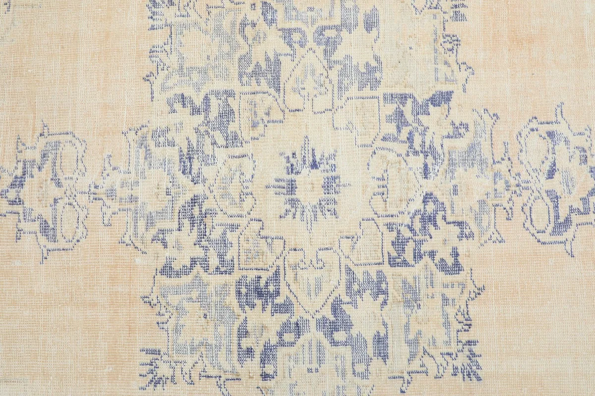 Close-up overhead view showcasing the central blue medallion motif and beige field of the rug.