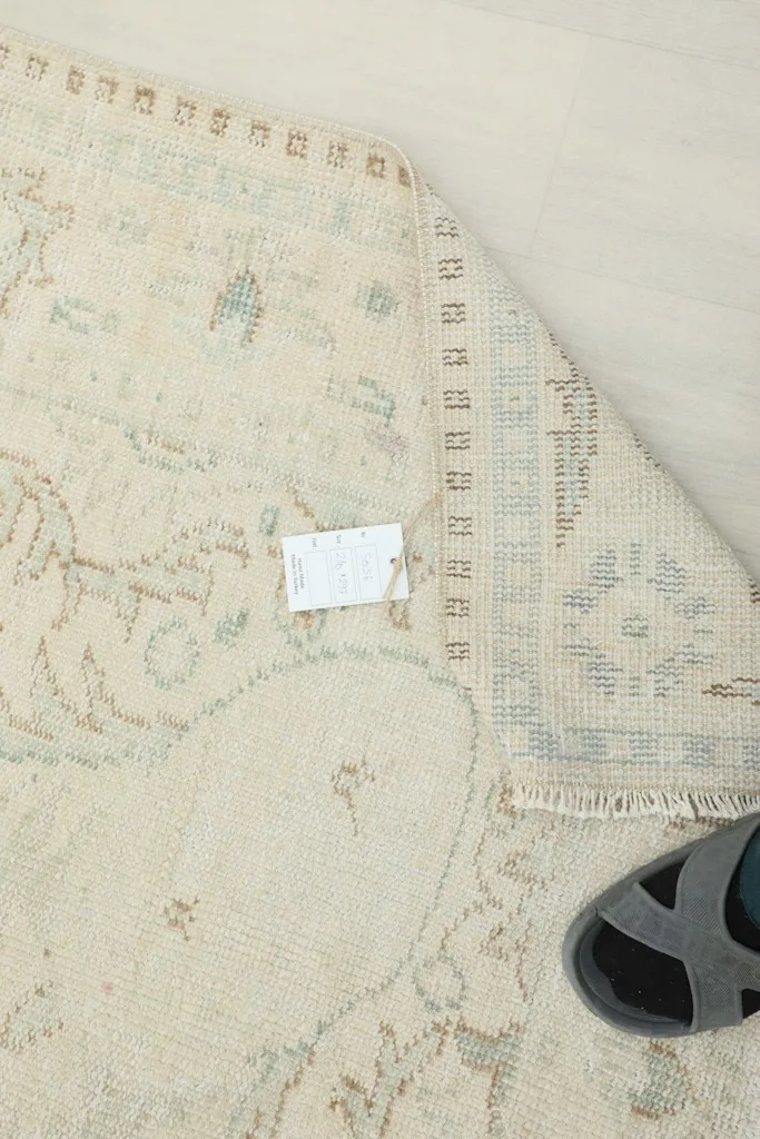 Overhead view of the rug's reverse side, showing the cotton foundation and a portion of the pile