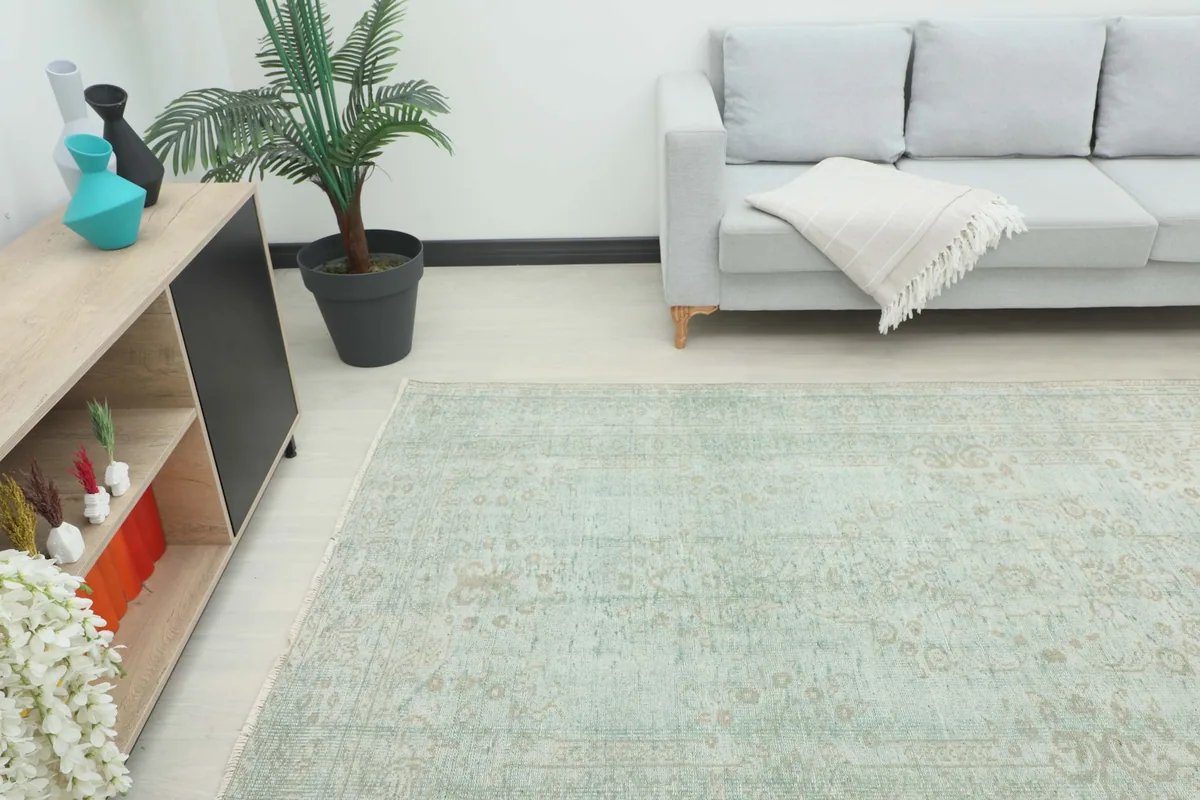 Full view of the green vintage rug placed in a living room with a gray sofa