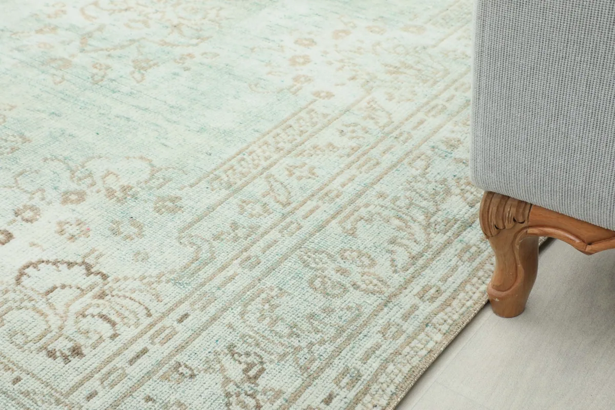 Close perspective of the rug next to a sofa leg, highlighting the border and field