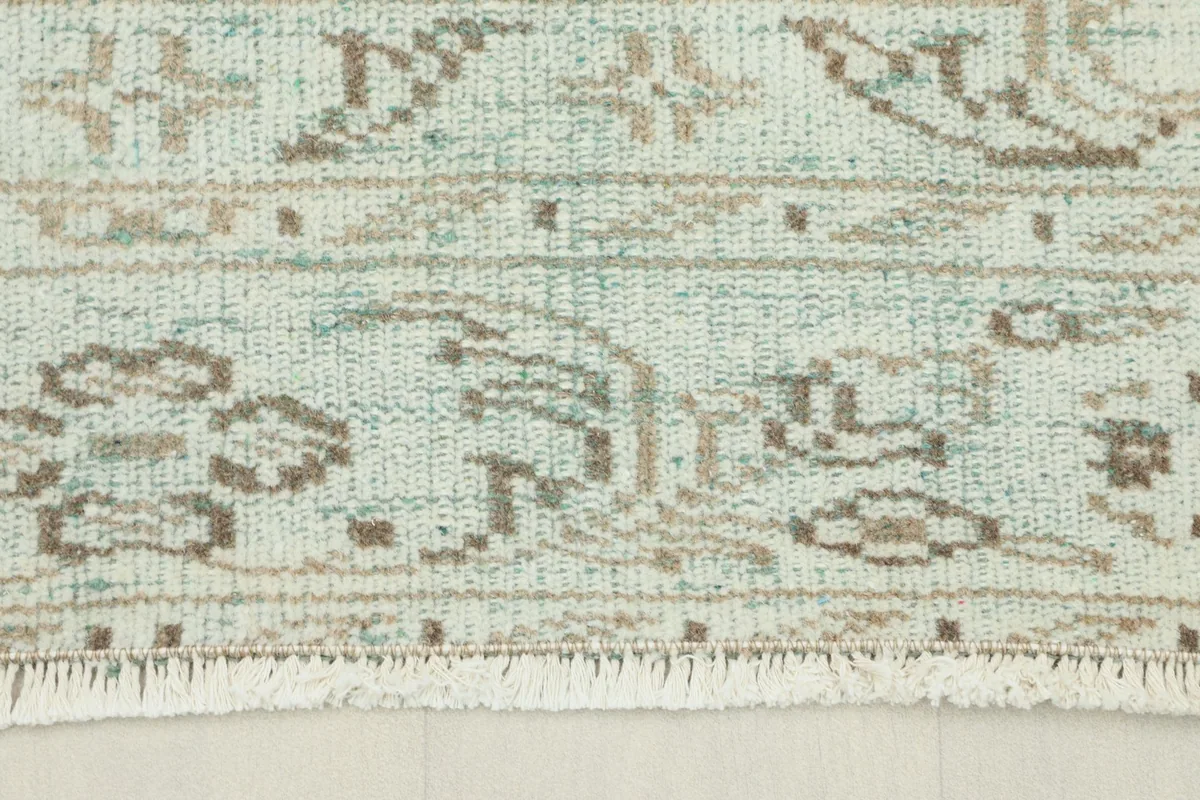 Close-up view of the rug's border and fringe showing geometric patterns