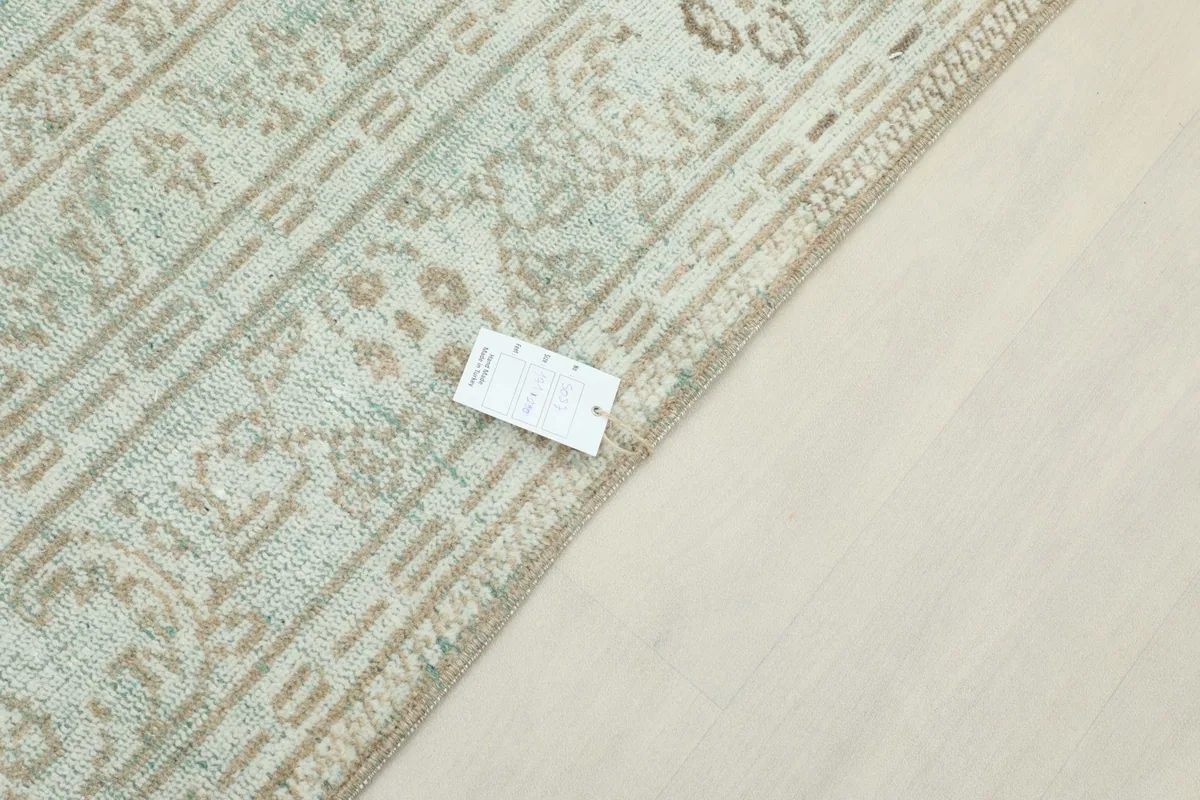Corner of the rug with a product tag, displaying the weave and color variations