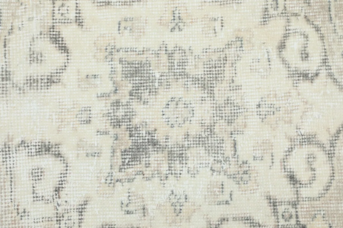 Close-up of the beige field showing faded geometric patterns and wool texture