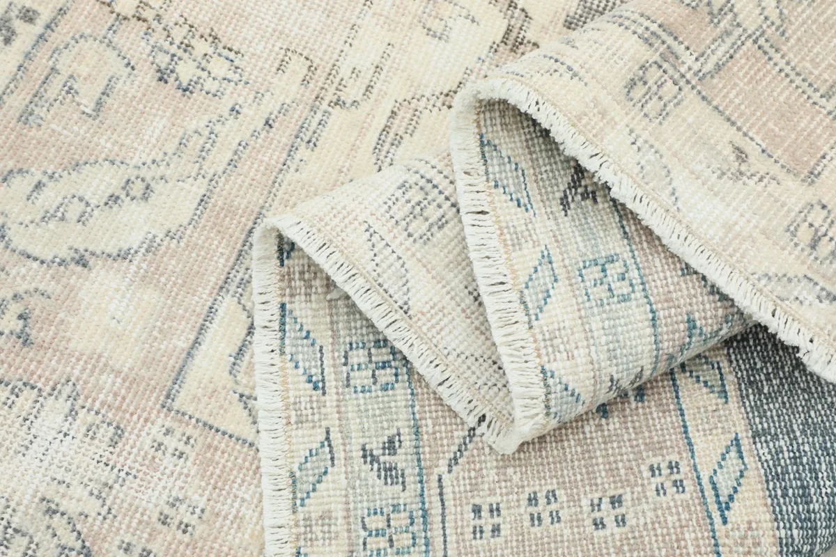 Folded section of the rug showing the reverse side with visible knotting and light blue threads
