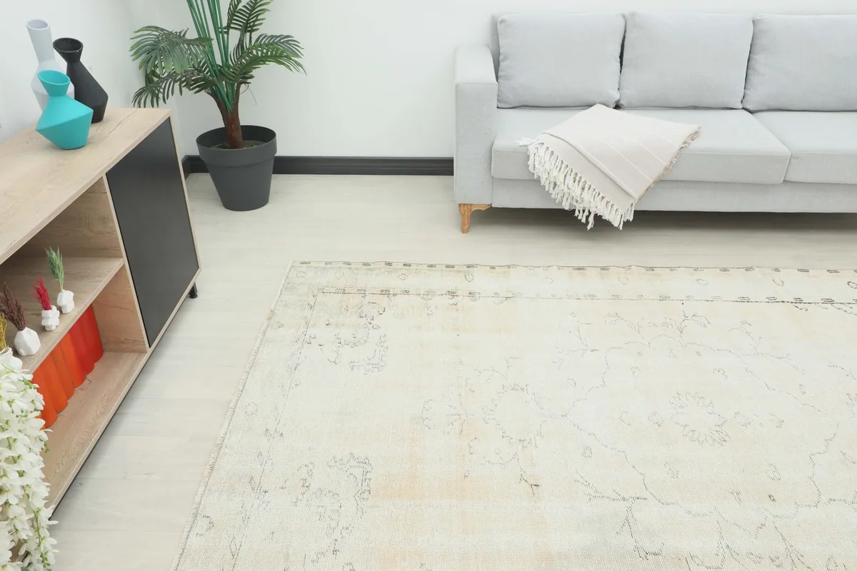Angle view of the ivory rug in a room, showing its placement next to a sofa and cabinet