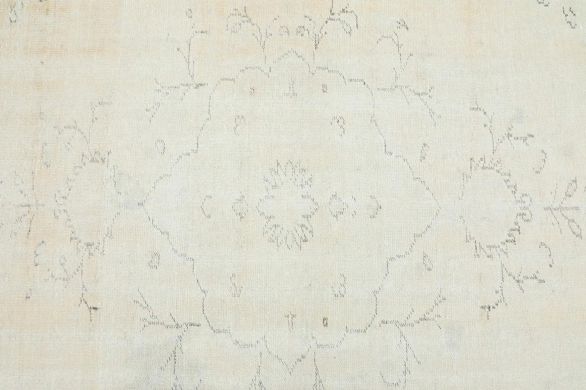 Detailed view of the faded central medallion motif and surrounding floral patterns on the ivory rug