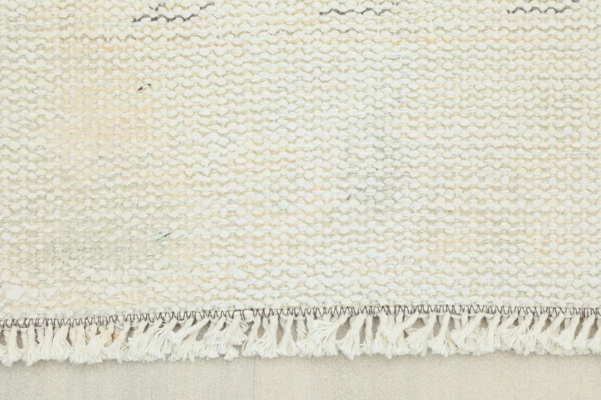 Close-up view of the hand-knotted fringe and the tightly woven back of the vintage wool rug