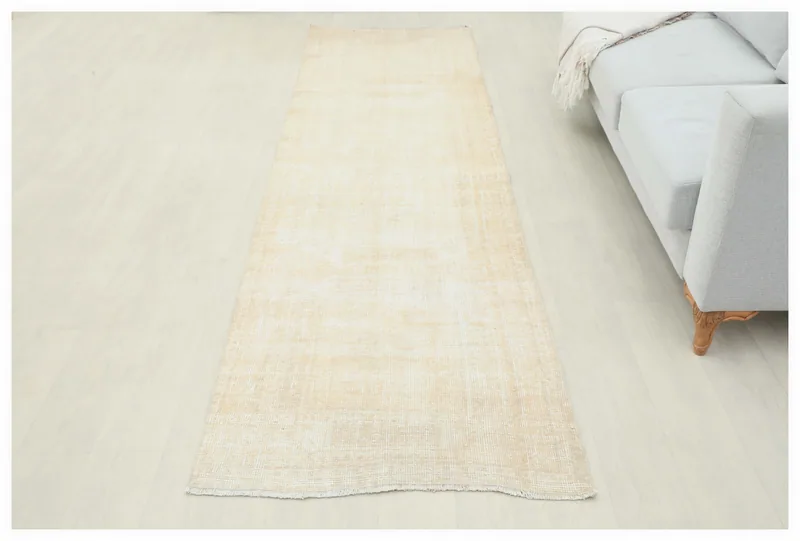 Full overhead view of the beige vintage Anatolian runner rug on a light floor.