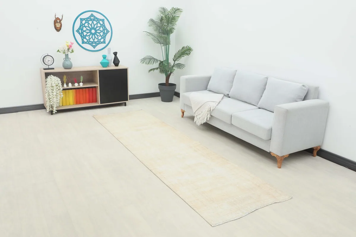 Runner rug placed in a room setting next to a sofa and cabinet, showing its length and scale.