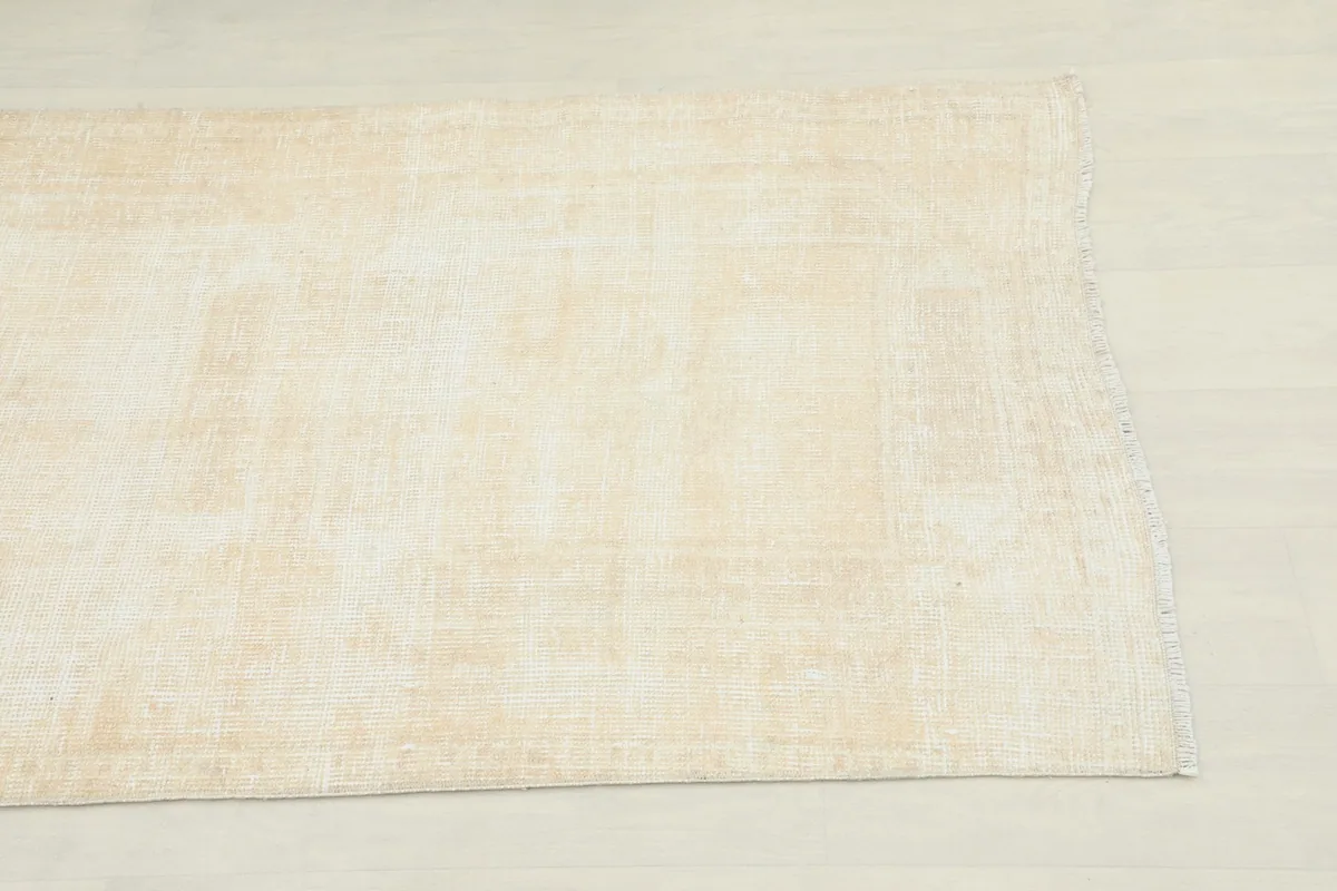 Close-up view of one end of the runner rug, showing the subtle texture and faded patterns.