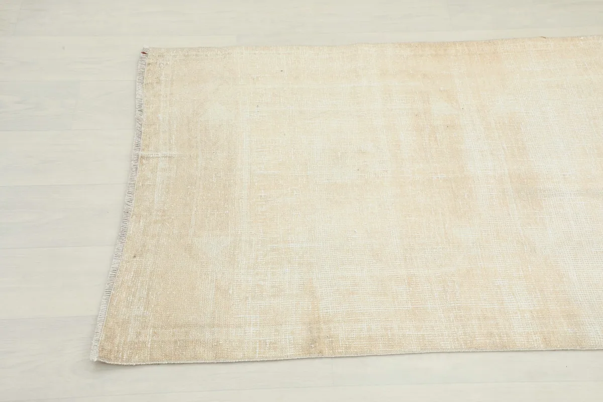Close-up view of the opposite end of the runner rug, detailing the worn texture and color variations.