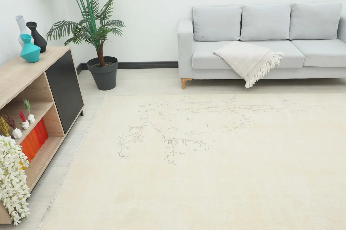 Overhead view of the large cream area rug in a room with a sofa and side cabinet.
