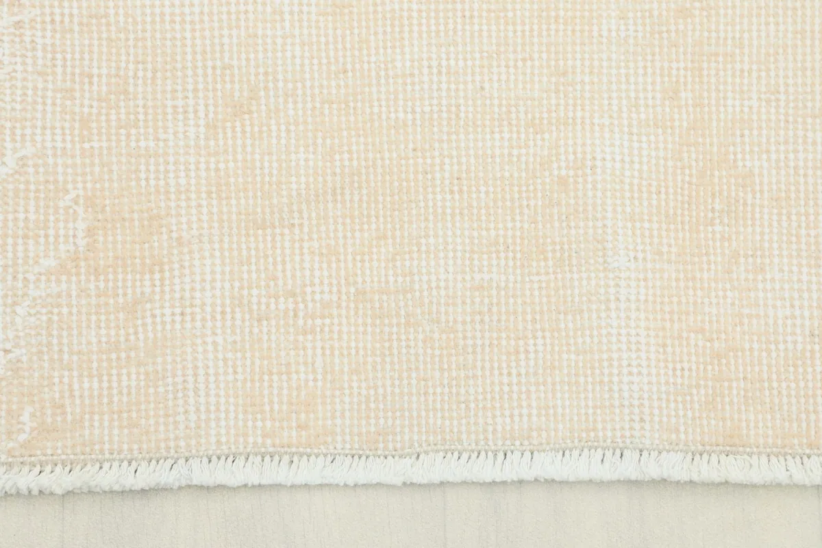 Close-up view of the low wool pile and tight weave of the cream vintage area rug.