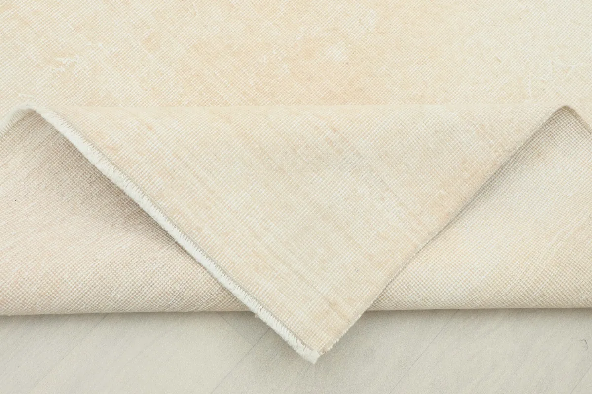 Folded corner revealing the cotton foundation and reverse side of the hand-knotted vintage rug.