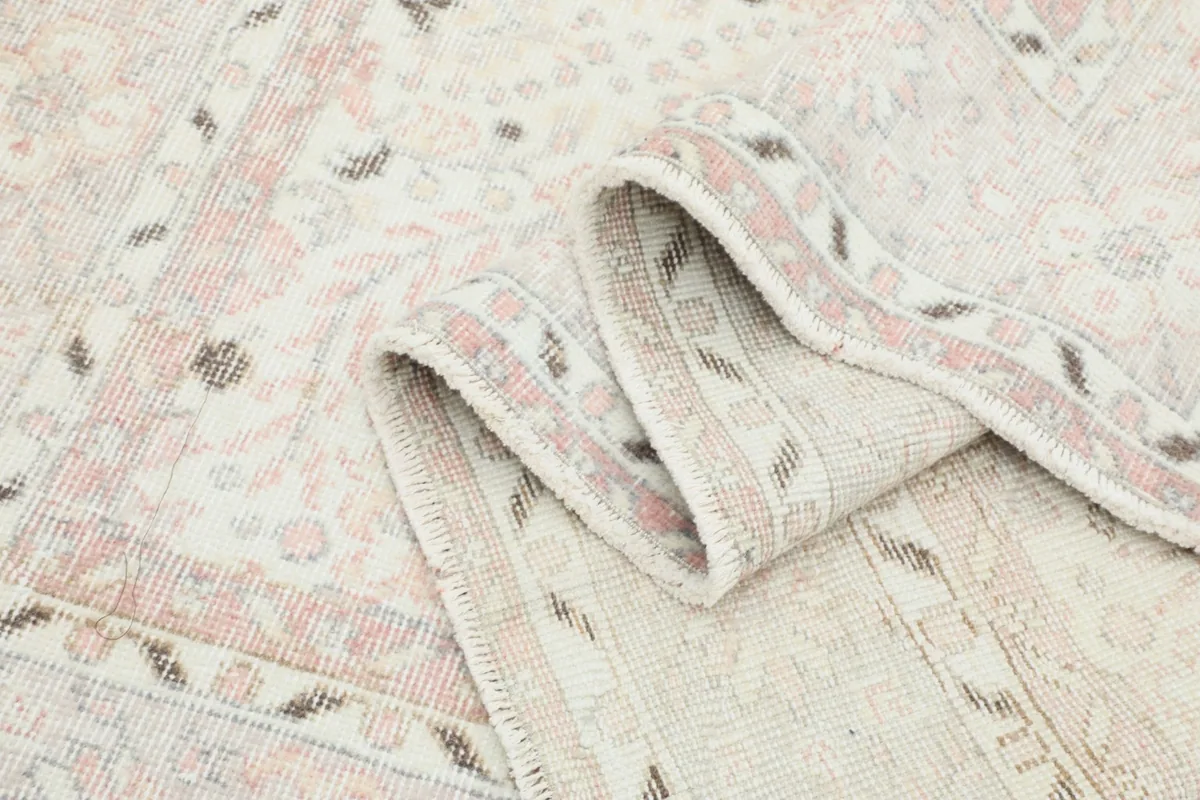 Close-up of the rug's low wool pile texture and the gentle, even wear across the surface.