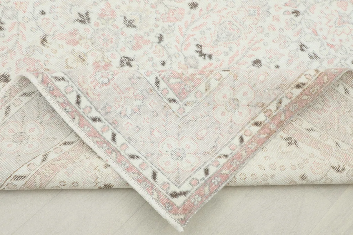 Folded corner of the rug revealing the hand-knotted construction and the cotton foundation.